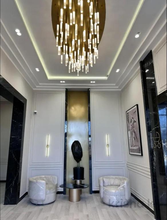 a lobby with two chairs and a chandelier at Designer Apartment with Mountain View in Almaty