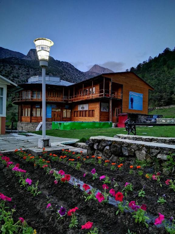 a house with a light pole and flowers in the yard at Artuch Camp - Fan Mountains in Yakkakhona