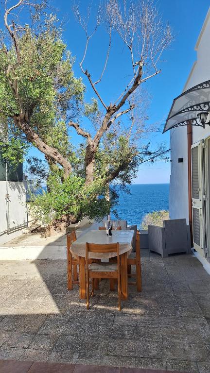 a wooden table and benches with a view of the ocean at A-mare Casa vacanza in Gagliano del Capo