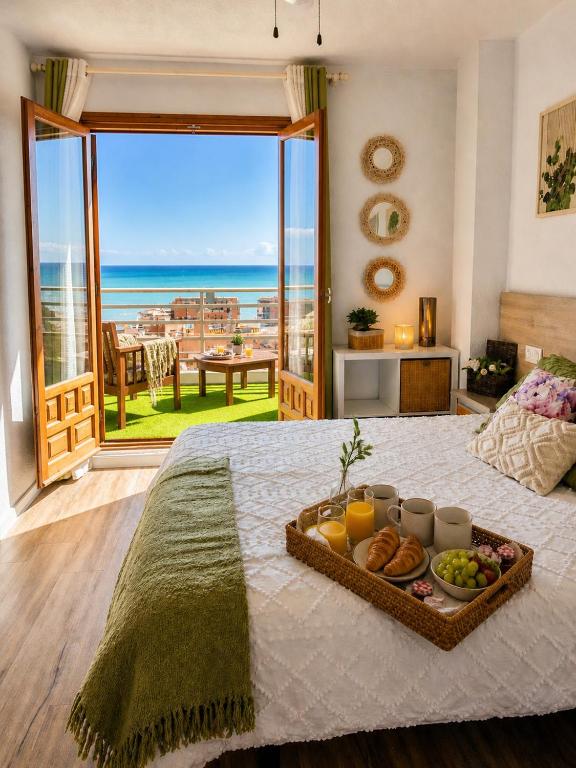 a tray of food on a bed with a view of the ocean at Costamar bungalow familiar, piscina y terraza, a 5 min de la playa in Arenales del Sol