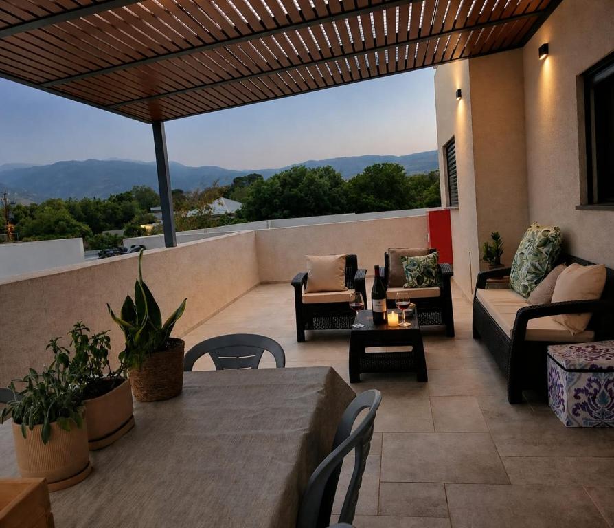 a patio with a table and chairs on a balcony at נוף לחרמון דפנה in Dafna