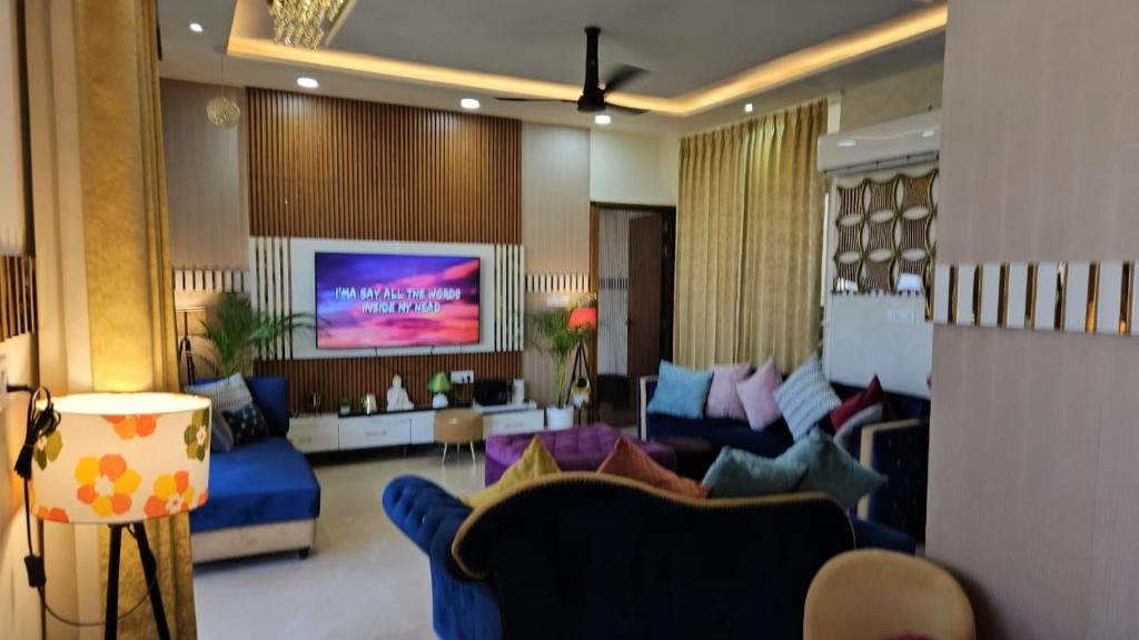 a living room with blue couches and a flat screen tv at Lux Bliss Bed & Breakfast in Amritsar