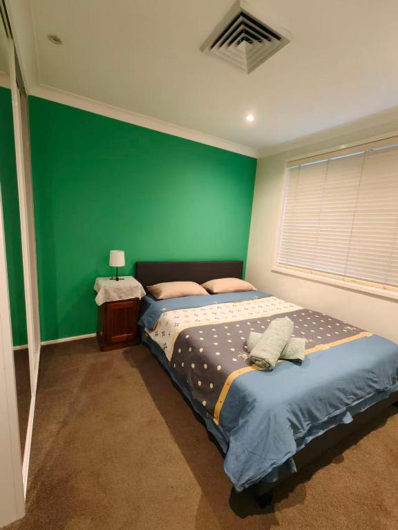 a bedroom with a green wall and two beds at Bright Double Room N Winston Hills in Toongabbie