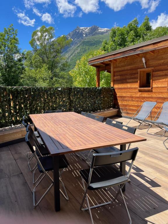 a wooden table and chairs on a deck with a cabin at le saint genest in Vallouise