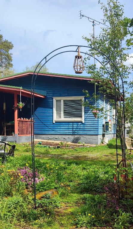 a blue house with an arbor in front of it at Blue House Nature Retreat with Private Garden in Sastamala