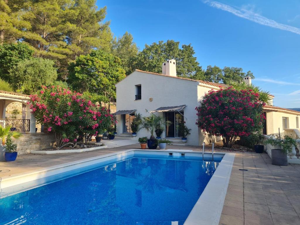 a villa with a swimming pool in front of a house at Villa Manoe in Draguignan