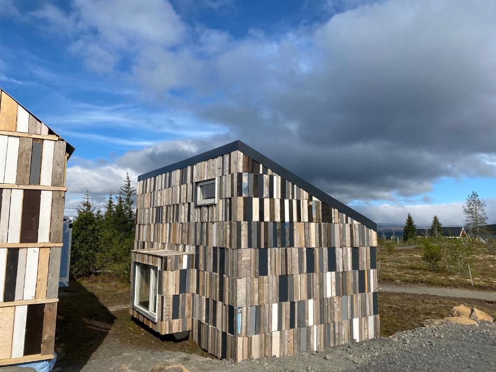 a house constructed of wooden panels next to a building at Guesthouse With Lake View in Veiðilundur