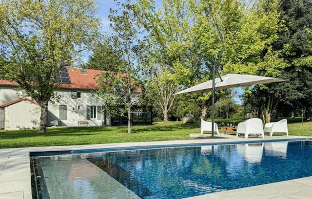 a swimming pool with two chairs and an umbrella at Domaine de Gans in Gans