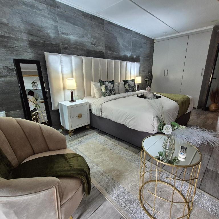 a bedroom with a bed and a chair and a table at Bosveld In Die Stad Lodge in Alberton