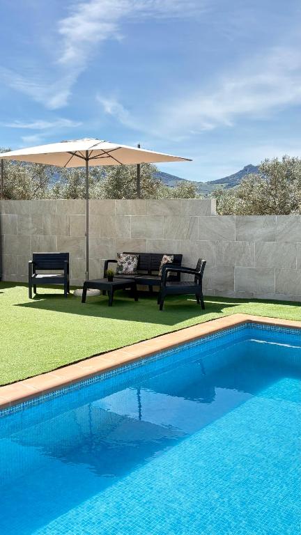 a bench and an umbrella next to a swimming pool at Casa Rural Cortijo Cerro Limon in Málaga