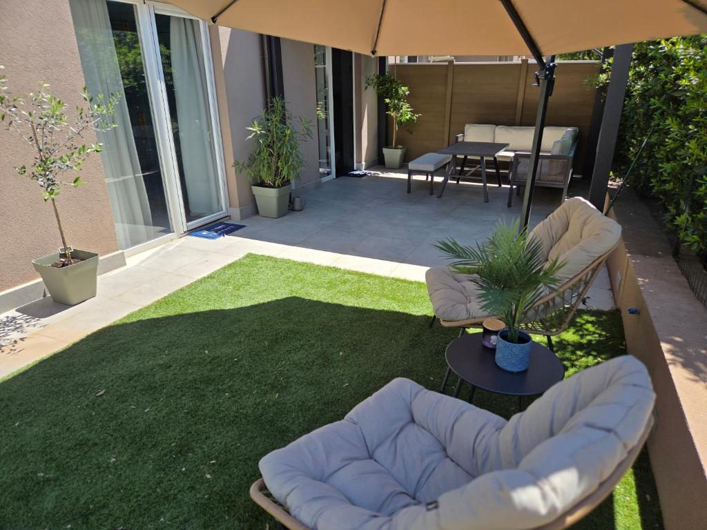 a patio with chairs and an umbrella and grass at Apartman Dea in Mali Lošinj