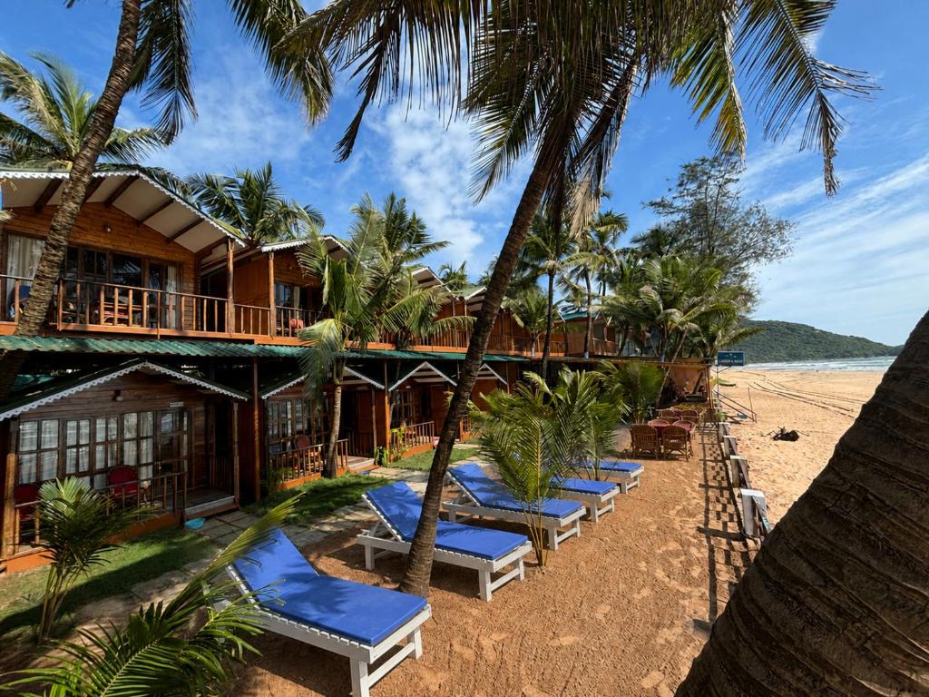 a resort on the beach with lounge chairs and palm trees at Jardim a Mar in Agonda