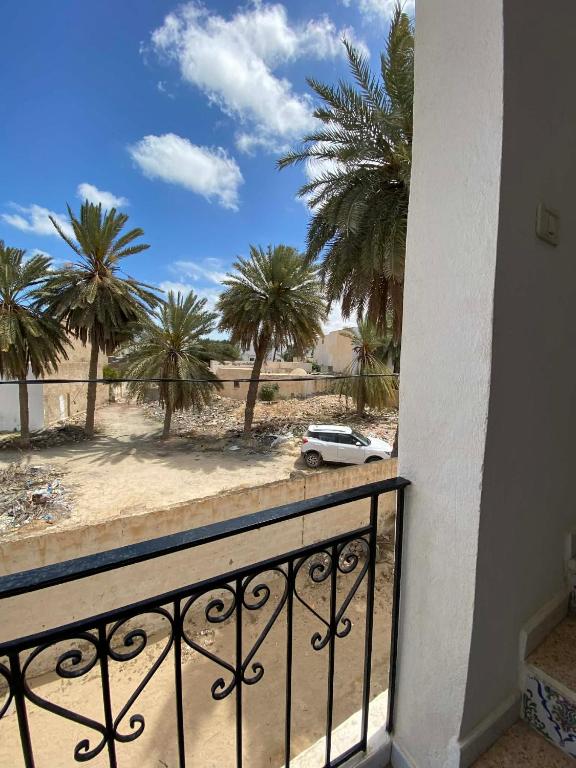 a balcony with a car on the beach with palm trees at Djerba Sérénité in Houmt Souk