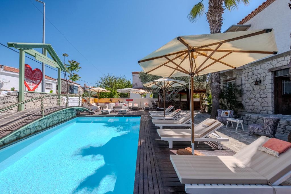 a swimming pool with lounge chairs and an umbrella at B House Alaçatı in Alaçatı