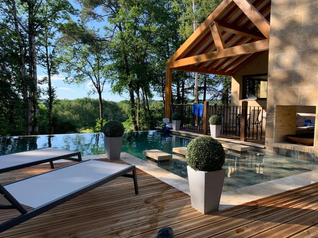 a house with a swimming pool and a wooden deck at Villa de Standing, Climatisation, Piscine chauffée & Nature in La Chapelle-Saint-Aubin