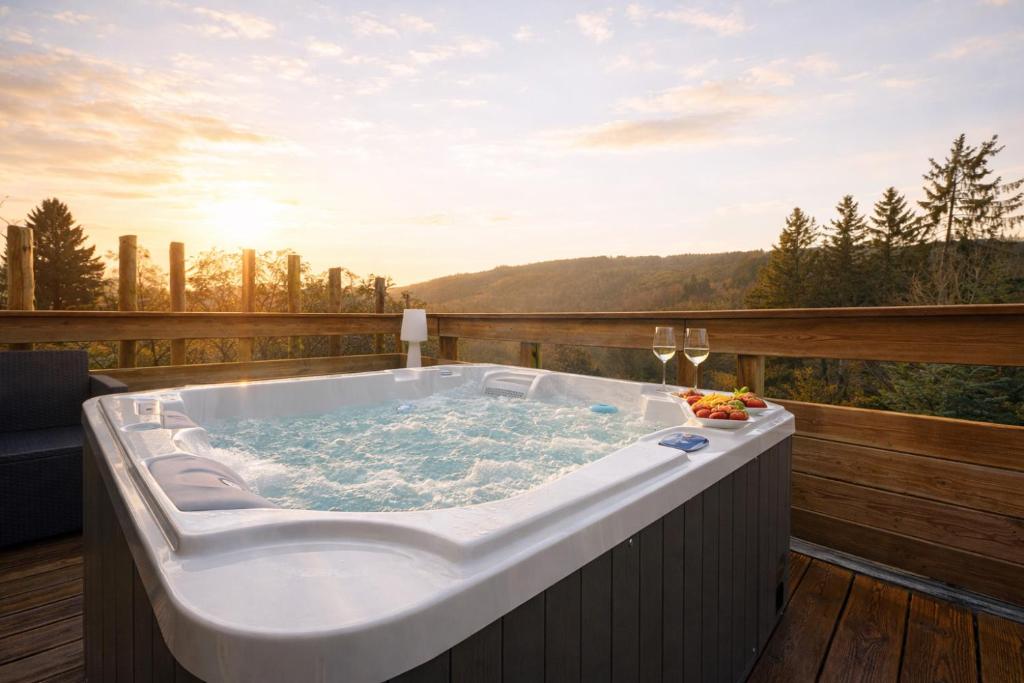 a jacuzzi tub on a deck with a view at Le lofty in Stoumont