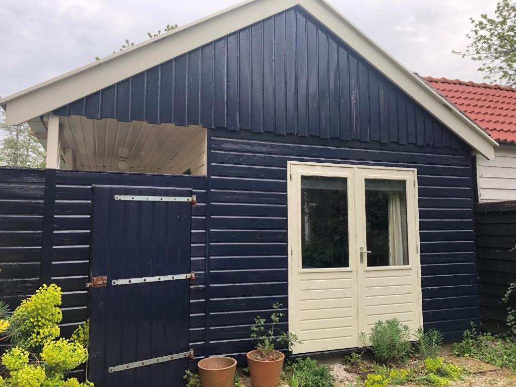 a navy blue shed with a white door at De Merel in Pieterburen