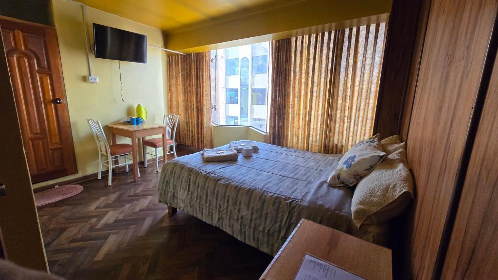a hotel room with a bed and a table and a window at Hostal La Casa del Sol in Juliaca