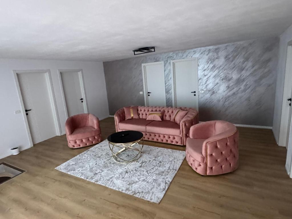 a living room with two pink chairs and a table at Casa din Frasin in Poiana Mărului
