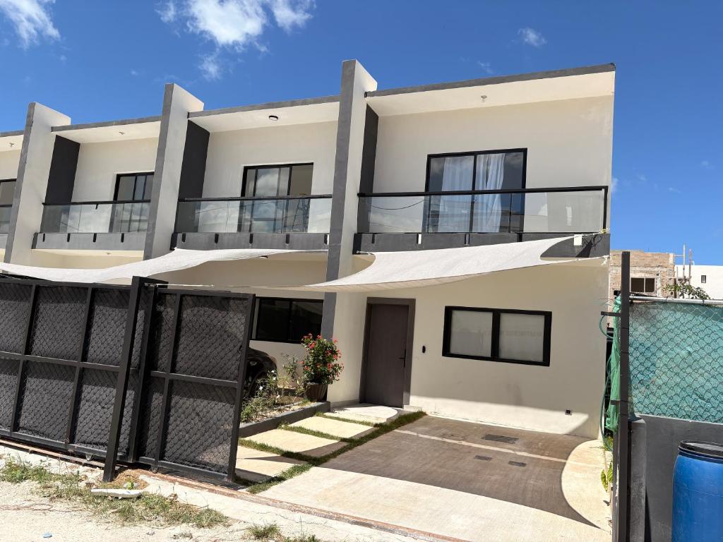 a white house with a fence in front of it at Apartamento completo punta cana in Punta Cana