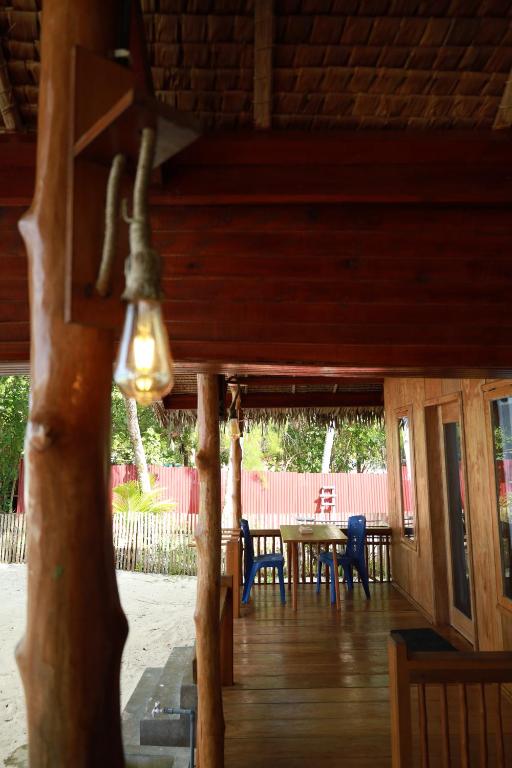 a wooden porch with a table and chairs at Buggei Surfcamp Mentawai in Katiet