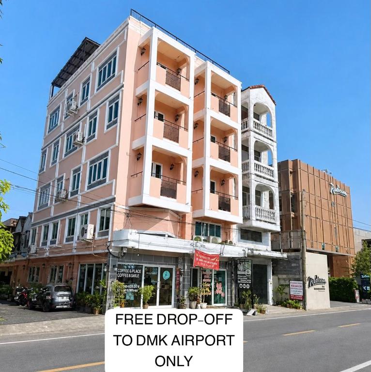 a pink apartment building with a sign for free drop off to drink airport only at Hoppers Place Donmuang in Bangkok