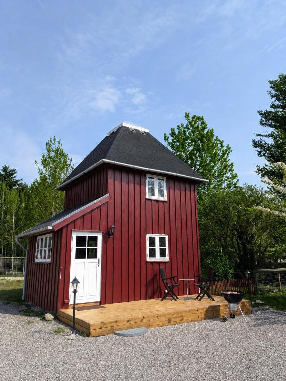 a red barn with a white door and a porch at Stevns Birkevang The Silo - Rural refuge in Faxe