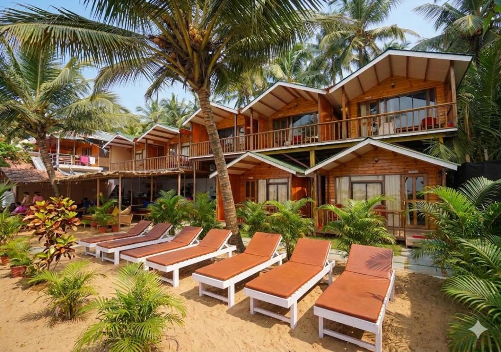 a resort on the beach with lounge chairs and palm trees at Sonho do Mar in Agonda