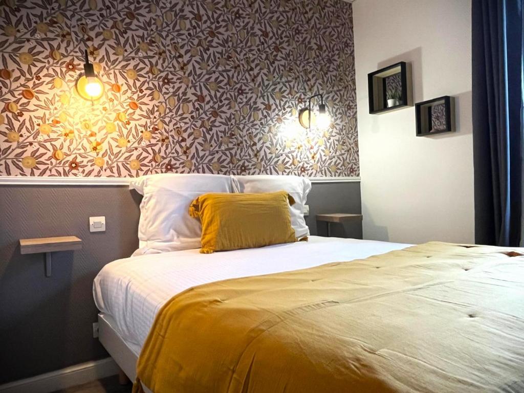 a bedroom with a large bed with a yellow pillow at Hôtel Maisons Delphine - Le Cottage in Villers-sur-Mer