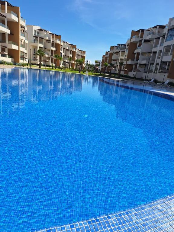 a large blue swimming pool in front of some apartment buildings at Nouvel appartement élégant à Cabo - Vue sur la piscine et proche de la plage in Cabo Negro