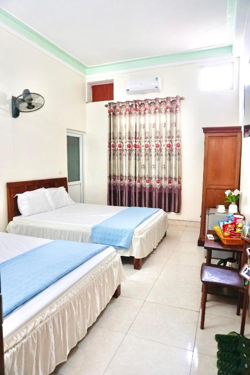 a hotel room with two beds and a table at Nhà nghỉ Việt Mến in Sầm Sơn