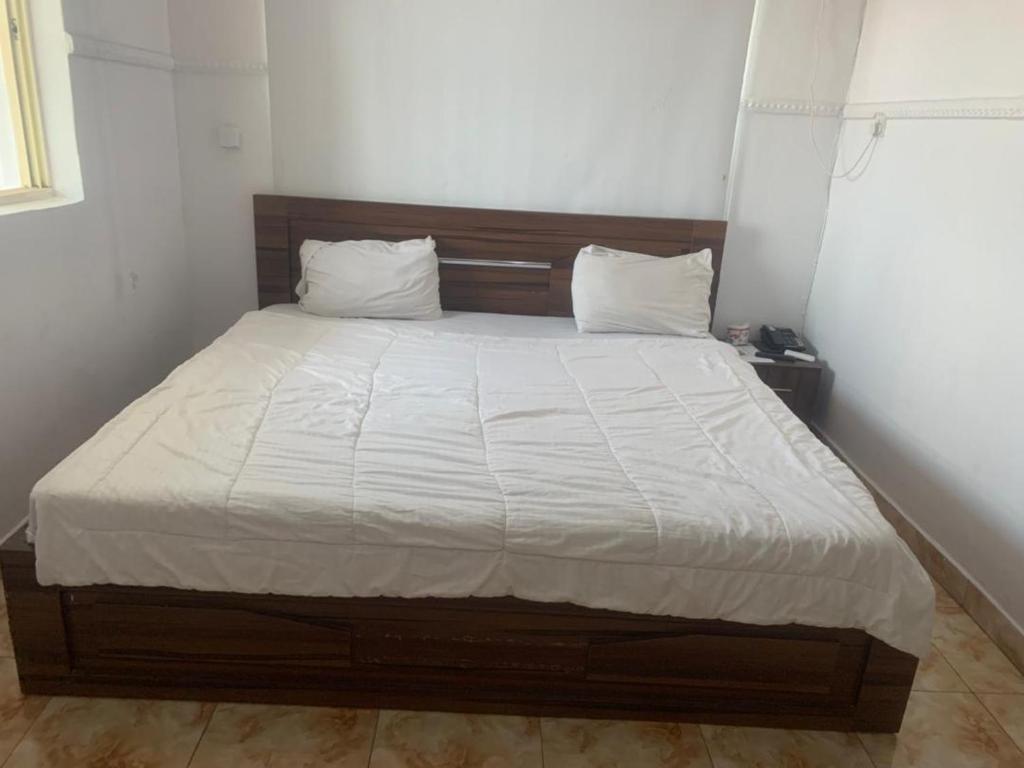 a bed with white sheets and pillows in a room at Beulah House Lounge in Ibadan