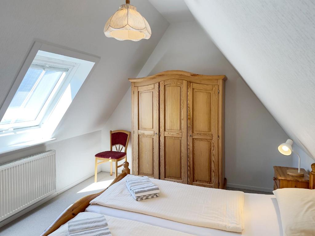 a attic bedroom with a bed and a wooden cabinet at Haus *Üüs Aran* Wohnung Nr. 6 in Nebel