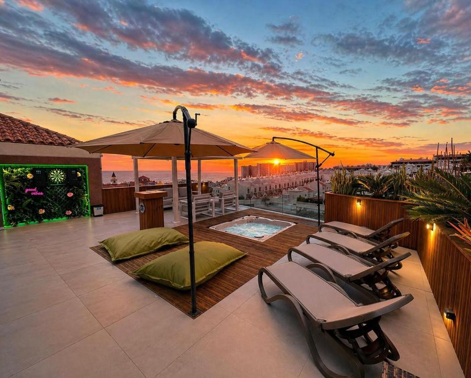 a patio with chairs and a pool and a sunset at Calma Paraíso Jacuzzi Sea View in Playa Paraiso