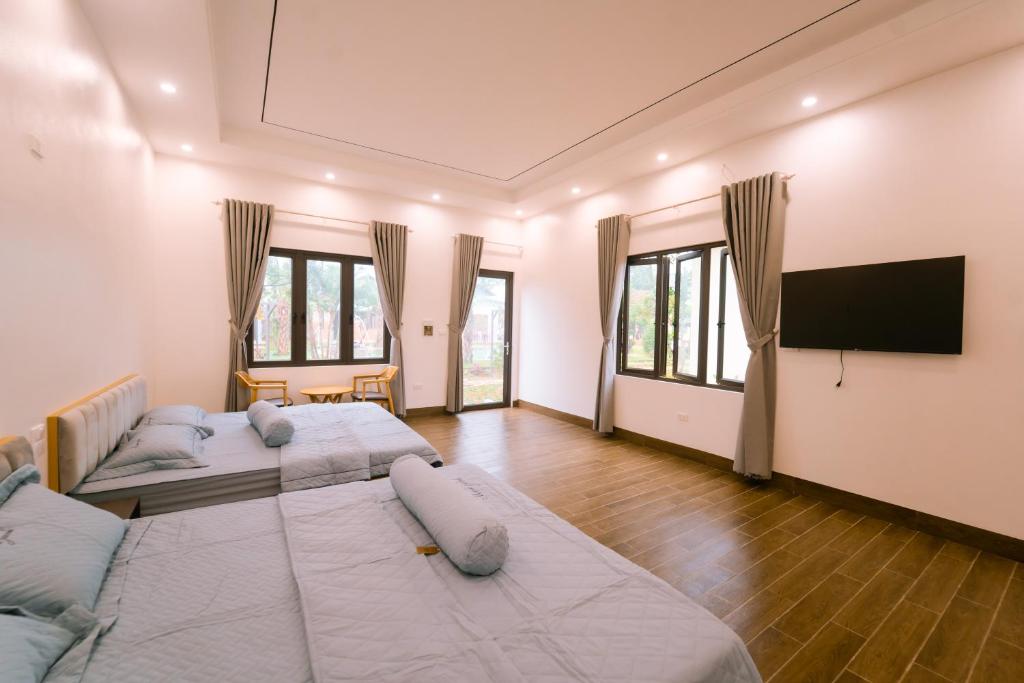 a bedroom with two beds and a flat screen tv at Đồi Bông Village in Mục Uyên