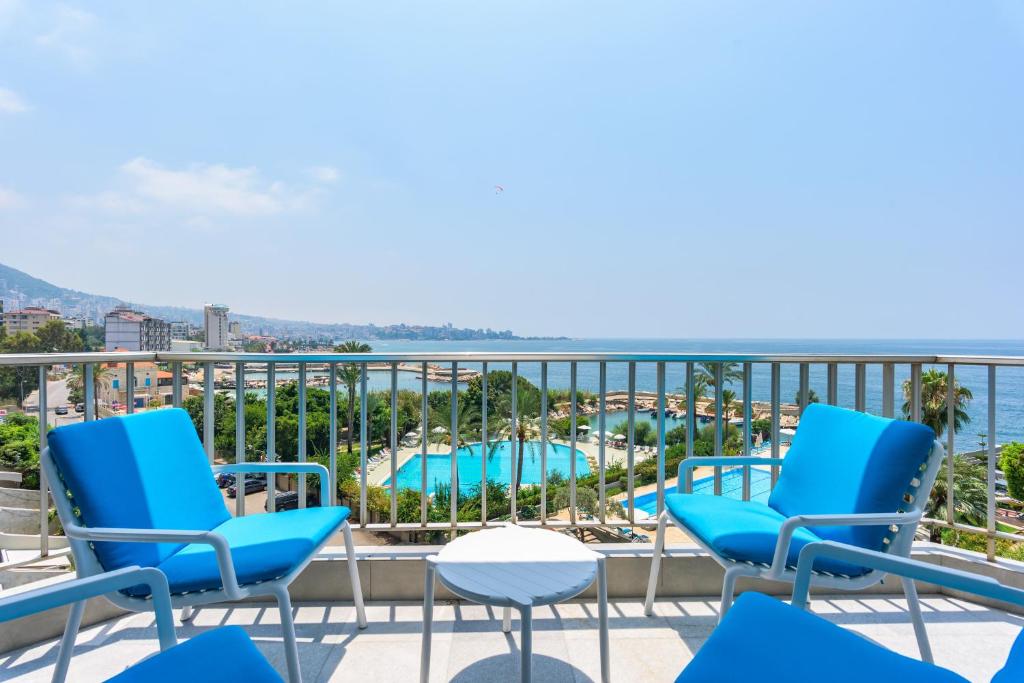 a balcony with blue chairs and a swimming pool at Bay B Blu,Modern 1BR Chalet -Seaview in Ed Dkârîne