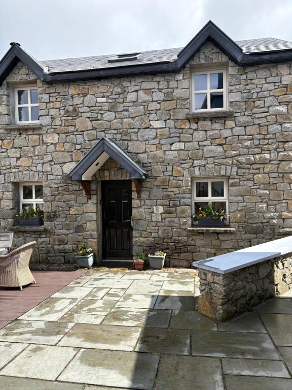 a stone house with a bench in front of it at Roundstone Retreats Abbys cottage in Roundstone