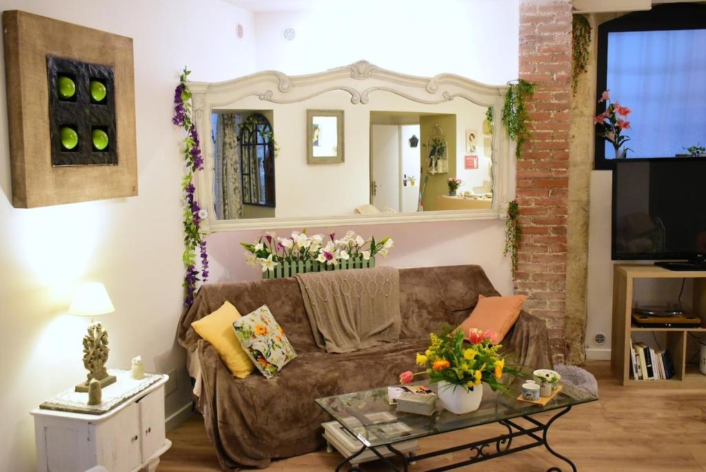 a living room with a brown couch and a mirror at Flor de Lys - Centre historique in Auch