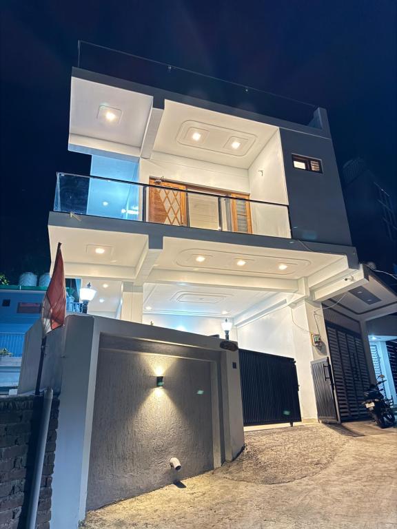a large white building with a balcony at night at Singh Kainchi Dham Villa in Bhowāli