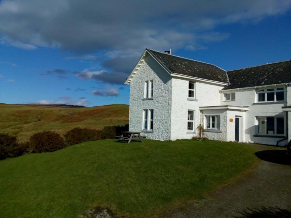 a white house with a picnic table on a lawn at Scoor House - Laggan in Bunessan