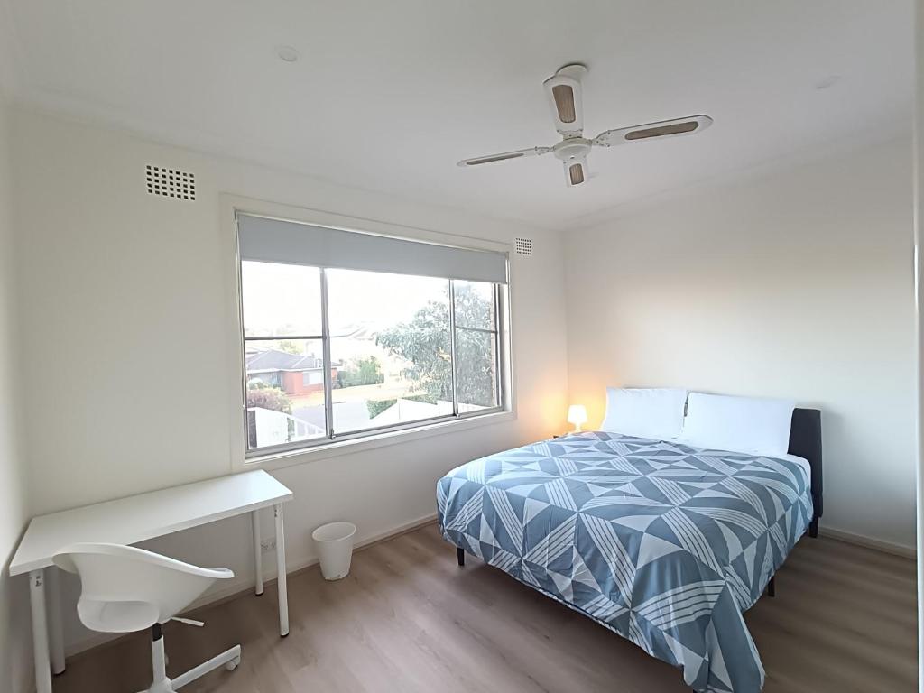a bedroom with a bed and a desk and a window at Spacious and Comfortable Queen Room - NM1 in Merrylands