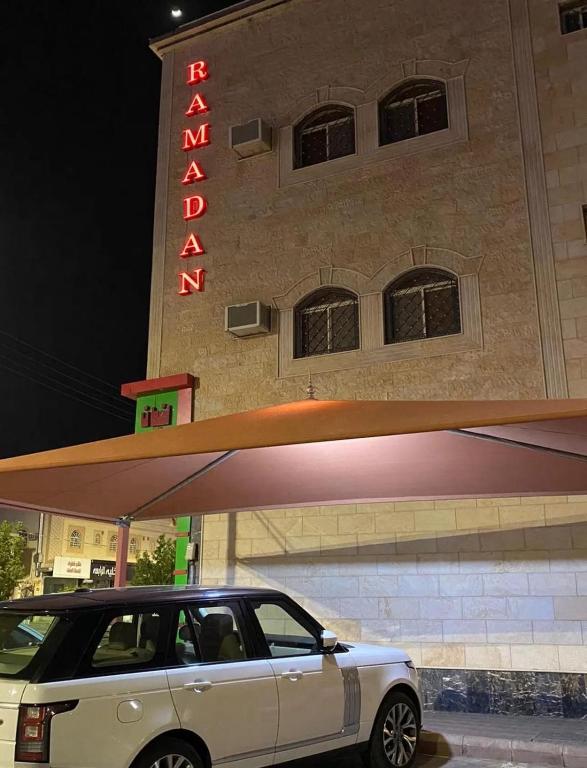 a car parked in front of a building with a neon sign at رمادان تربة للشقق المخدومة in Turbah
