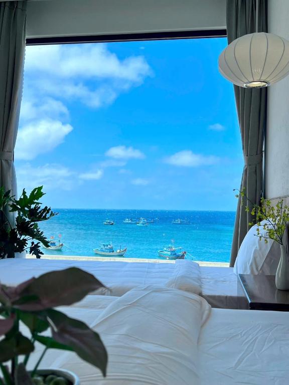a bedroom with a large window looking out at the ocean at Coco Villa 2 in Cu Lao Thu