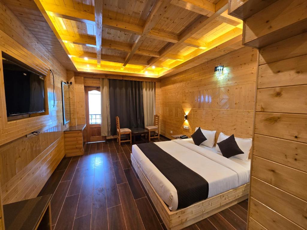 a bedroom with a large bed and a television at The Park Green Resorts in Manāli