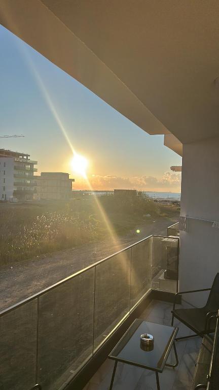 a view of the sunset from a balcony with a table at TheBlueEscape Apartment in Năvodari