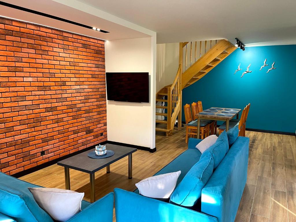 a living room with a blue couch and a brick wall at AchKaszuby domki nad morzem in Puck