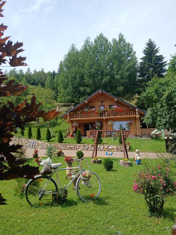 a bike parked in the grass in front of a log cabin at Cabana La Bălănuț din Bucovina in Colacu
