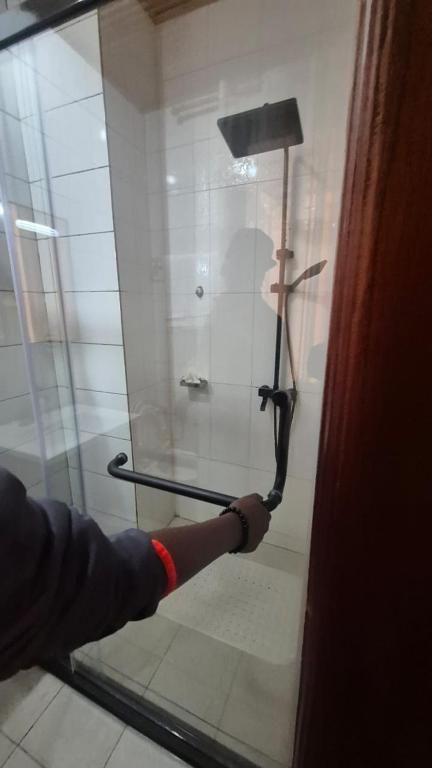 a person opening a glass door with a handle at Kaze Consolidate Home Inn in Kigali