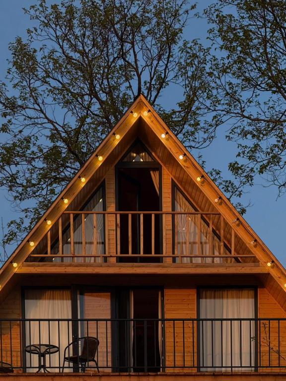 a log cabin with a balcony and a tree at Greenside Buknari in K'veda Ulianovka