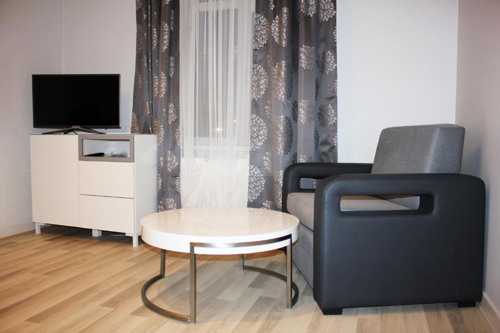 ein Wohnzimmer mit einem Stuhl, einem Tisch und einem TV in der Unterkunft Sky Apartments Riga in Riga